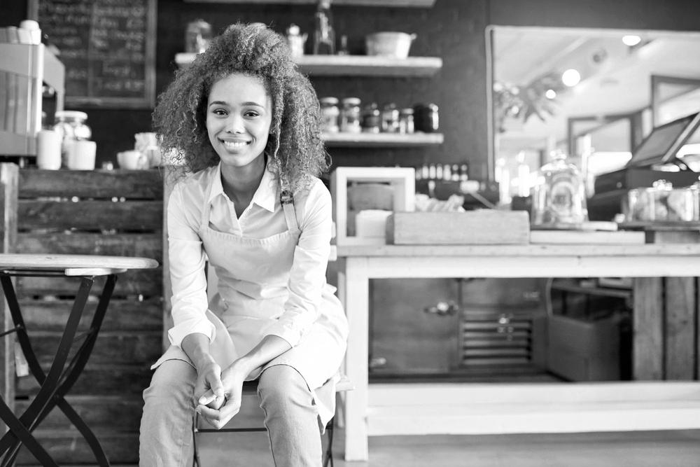 Female entrepreneur sitting in front of a table wearing an apron